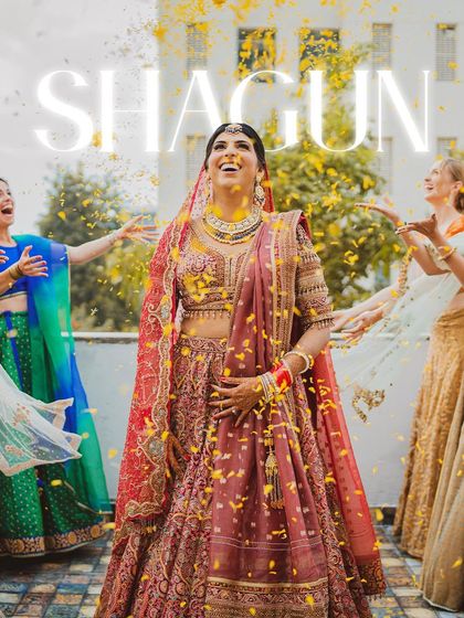 A moment of pure bridal bliss. The bride, Shagun, looks up with a joyful smile as her bridesmaids shower her with flower petals.