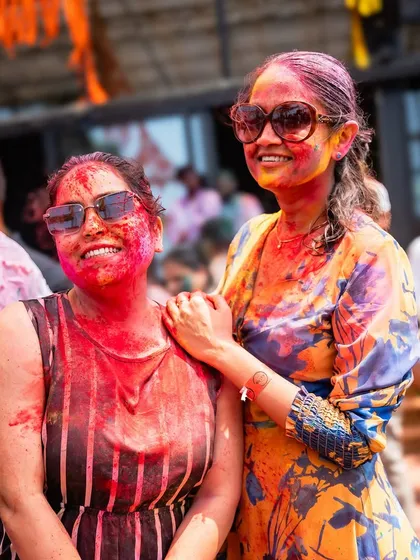 Guests smiling and covered in festive colors. We aim to create a welcoming atmosphere where everyone feels part of the celebration.