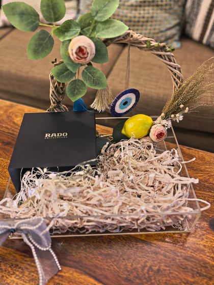 The beginning of the creative process for a groom's hamper. Here, a Rado watch box is placed in an acrylic tray, ready to be surrounded by curated items and floral arrangements that will bring the final vision to life.