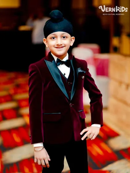 The definition of a little gentleman. This custom-made velvet tuxedo in a rich maroon features a classic satin lapel, designed for the most formal occasions. We ensure a perfect, comfortable fit so he feels as good as he looks.