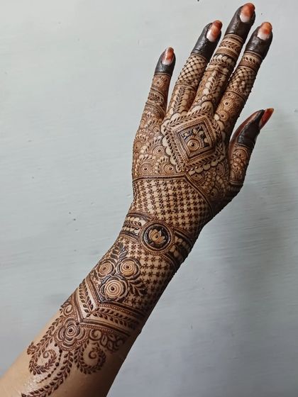 A complete view of an intricate back-hand design that extends up the arm. The pattern flows from a central geometric element, using a mix of grids and traditional motifs for a stunning effect.