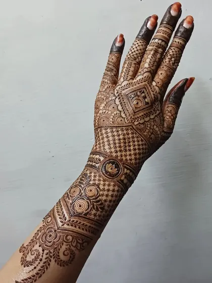 A complete view of an intricate back-hand design that extends up the arm. The pattern flows from a central geometric element, using a mix of grids and traditional motifs for a stunning effect.