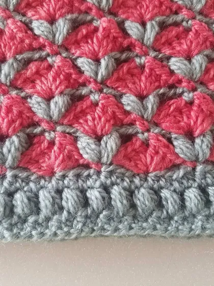 A detailed close-up of the blossom stitch pattern in pink and grey. The texture is created with a combination of simple stitches that I can teach you in my classes.
