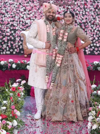 A lovely photo of the bride and groom against a wall of flowers. Her smile says everything about how she felt on her wedding day.