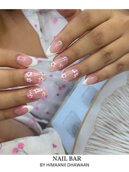 Sweet and simple floral art. This design combines classic French tips with nails adorned with tiny, delicate pink flowers.