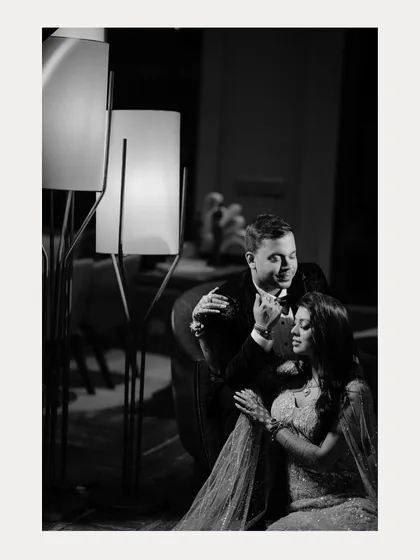 A quiet, romantic moment captured in black and white. This intimate portrait shows the couple in a tender pose, the soft lighting from the lamp creating a warm and timeless atmosphere.