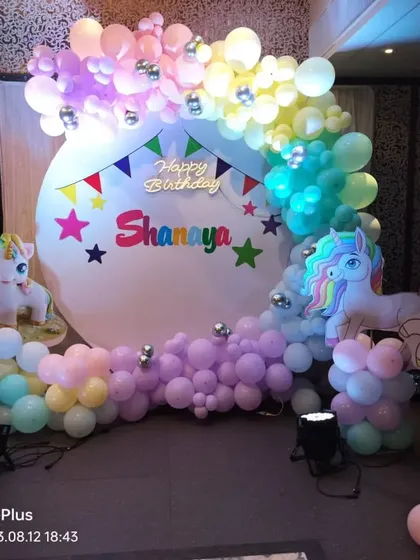 A colorful unicorn-themed party with a simple white circular backdrop that makes the pastel balloon garland and unicorn props pop.