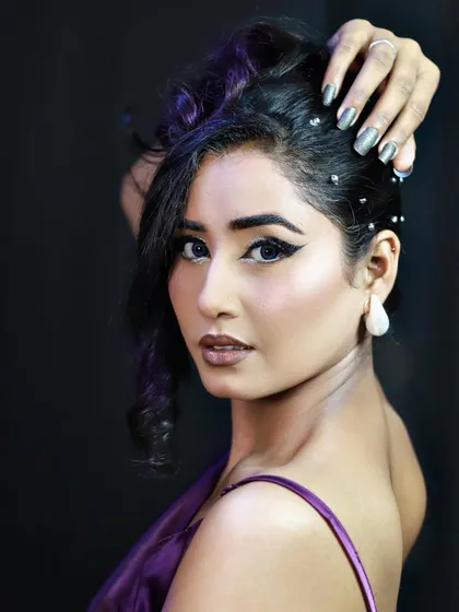 A purple-themed party look with a dramatic winged eyeliner and a messy-chic updo.