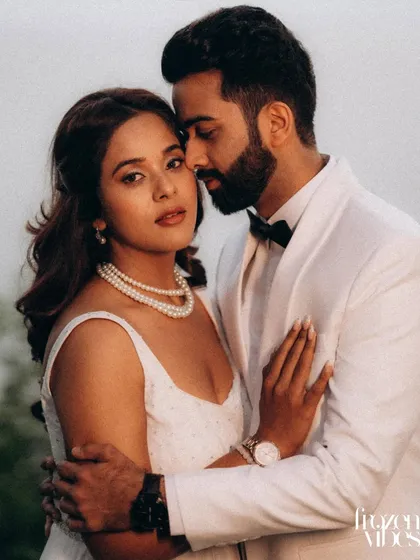 An elegant and classic portrait of Himanshu and Anushka. Her white dress and his tuxedo create a formal look that contrasts beautifully with the natural lakeside setting.