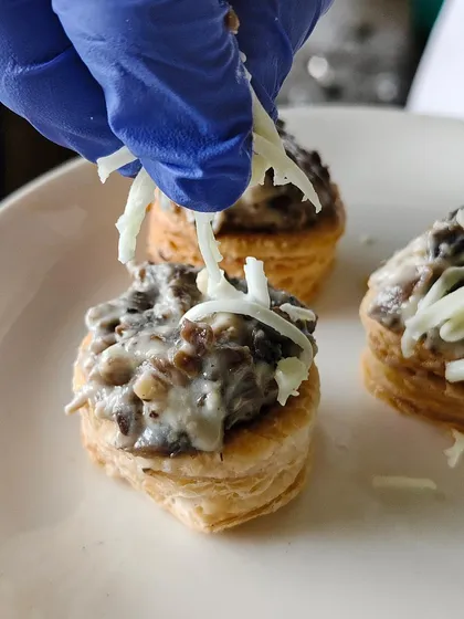 The final sprinkle of cheese on our creamy mushroom vol-au-vents. It's these small details that make our appetizers a highlight of any event.