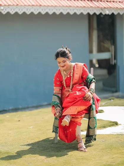A full-length shot of a happy bride, her intricate mehndi visible as she adjusts her saree. The mehndi is an essential part of her complete bridal look.