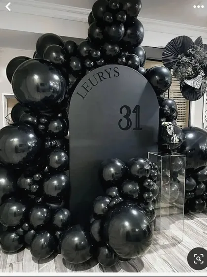 A bold and minimalist all-black theme for a 31st birthday. This striking design uses a custom black backdrop and a full arch of black balloons in various sizes for a modern, high-fashion look.