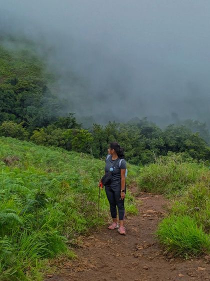 A trekker on the Netravathi trail, surrounded by lush greenery and mist.