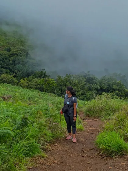A trekker on the Netravathi trail, surrounded by lush greenery and mist.