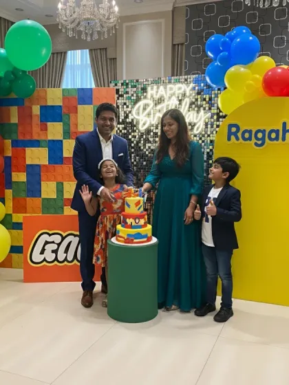 The family cutting the cake at a vibrant LEGO-themed birthday party. The colorful backdrop and themed cake stand make for a perfect cake-cutting photo.