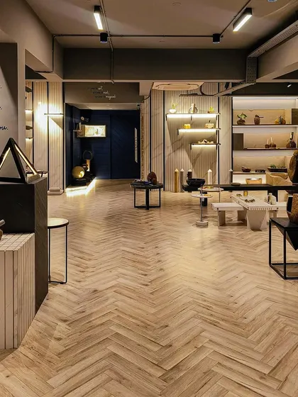An expansive look at the Paarkhi stone boutique, where a herringbone wood floor harmonises with neutral-toned walls and thoughtfully placed product displays. The design uses open space and strategic lighting to create a serene, gallery-like experience for customers.