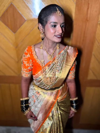 A beautiful profile of a traditional bride. The soft lighting highlights her glowing skin and the intricate details of her gold jewellery and embroidered blouse.