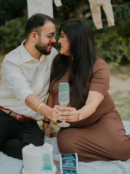 A sweet moment from a gender reveal photoshoot. The couple shares a toast, with the blue drink hinting at the exciting news they are about to share.