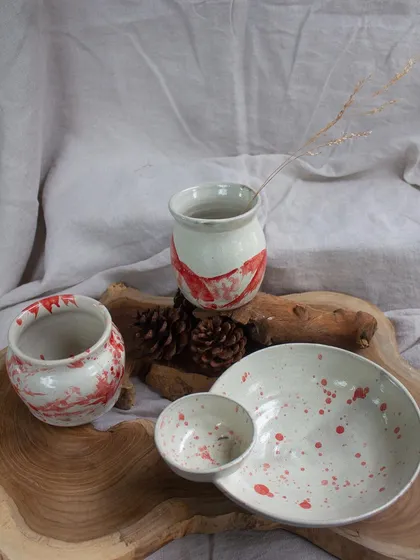 Another view of the red and white slip-decorated pieces, arranged on a rustic wooden slab.
