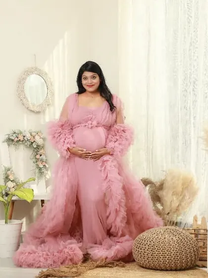 A glowing solo portrait of a mom-to-be in a beautiful pink ruffled gown. My studio’s lifestyle corner with its boho decor provides a warm and stylish backdrop for elegant maternity photos.