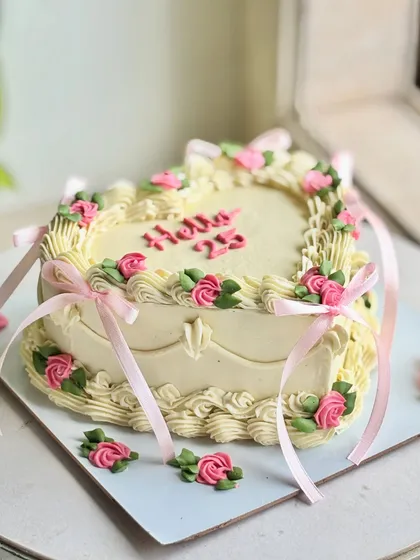 Heart-shaped but make it vintage. This dreamy 25th celebration cake features pastel rosettes, dainty pink bows, and intricate piping for a soft, romantic, and aesthetic vibe that’s made to be remembered.