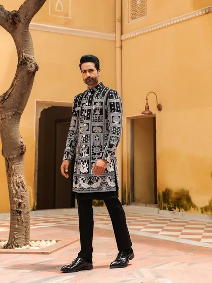Stand tall in a design that blends heritage with modern art. This unique black Indo-Western sherwani features a captivating block print design, offering a contemporary and artistic take on traditional groom's wear.