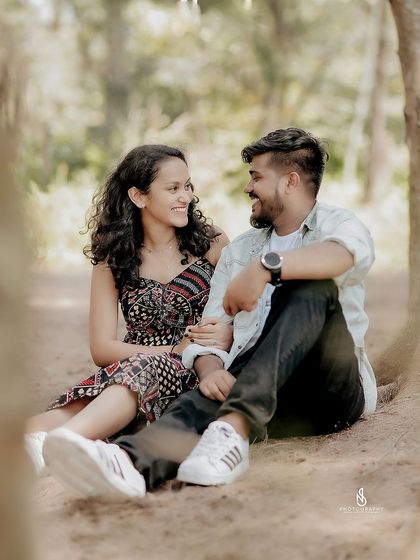 A sweet, intimate moment sitting together at the base of a tree. The soft, filtered light creates a gentle and romantic mood.