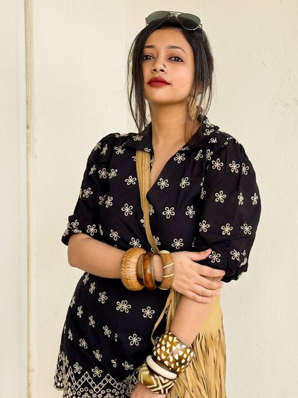 A close-up showing the embroidery on the romper and the stacked wooden bangles.