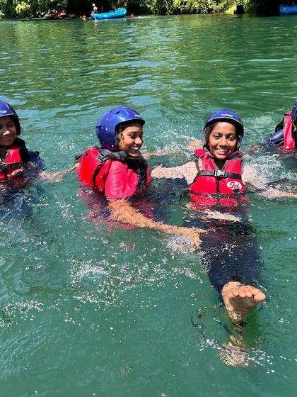 Four campers hold hands and float together, a simple moment of connection and fun in the water.
