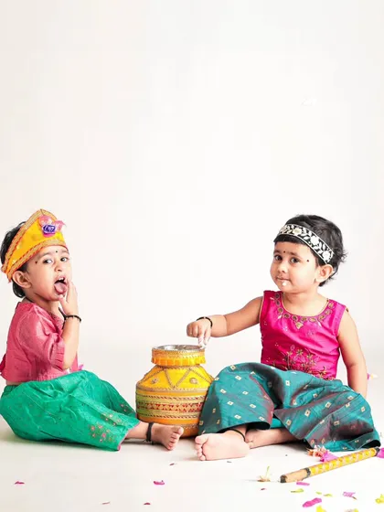 Two little friends or siblings sharing a pot of butter during a Janmashtami shoot. We love capturing the interactions and shared giggles between children.