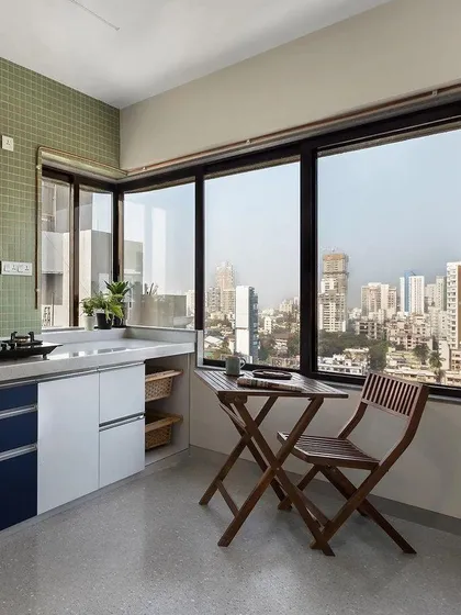 A compact kitchen designed to maximize space and views. We used light colors and a small, foldable breakfast table by the window to create a bright and airy spot for a morning cup of tea.