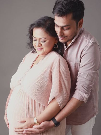 Dressed in soft pastel tones, this couple shares a quiet, loving moment. The focus is on their gentle embrace and the anticipation of their baby's arrival.