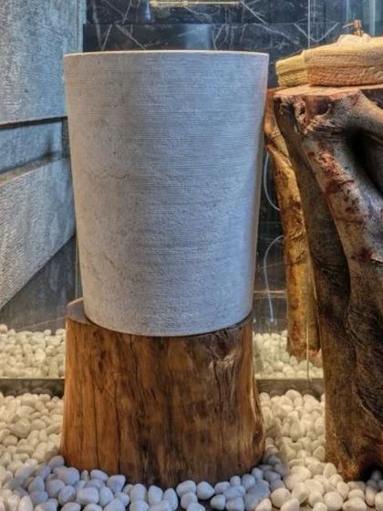This washbasin design is a study in natural harmony. A simple stone sink rests on a raw log, set against a backdrop of reclaimed wood and slate. The floor of white pebbles completes the look, bringing the five elements together in a small, tranquil space.