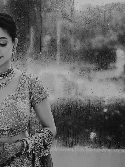 A moody, artistic bridal portrait captured on a rainy day in Mumbai. We see beauty in the elements, using the rain-streaked window to create a soft, painterly effect that is both melancholic and beautiful.