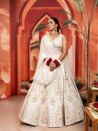 This serene white lehenga offers a vision of modern royalty. The intricate gold embroidery provides a beautiful contrast, creating a look that is both graceful and unforgettable.