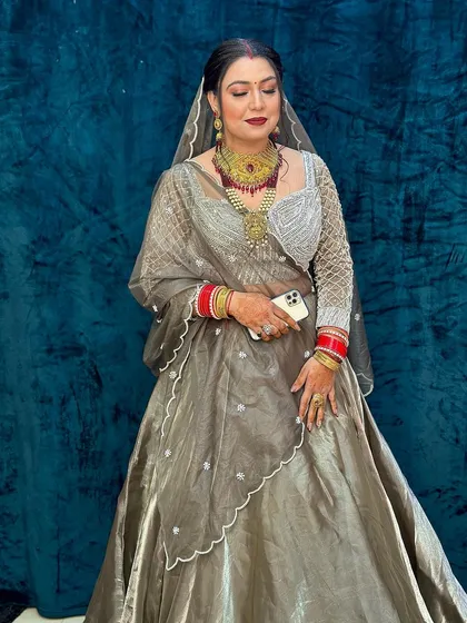 A full-length shot of a bride in a grey organza lehenga. The makeup is bold with a red lip, creating a beautiful contrast.