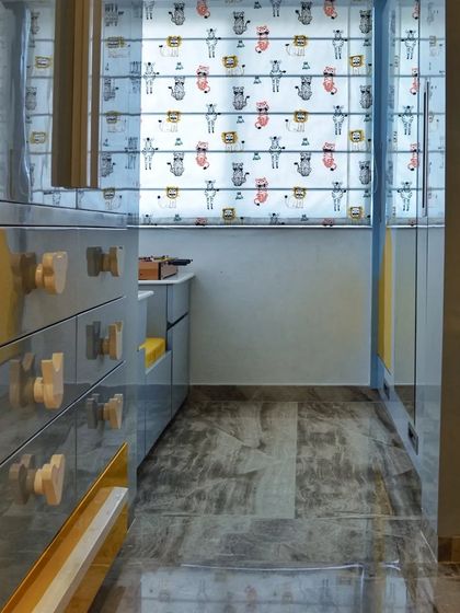 A view into the kids' room showing the glossy blue and yellow cabinets with custom handles, reflecting the fun patterned blinds in the background.