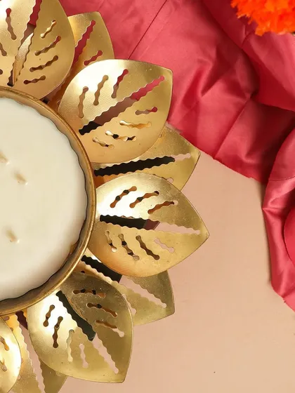 A detailed close-up of the multi-wick Lotus Urli, highlighting the smooth soy wax and the intricate design of the golden leaves.
