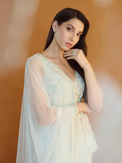Nora Fatehi looks ethereal in this white peplum and sharara set by Ritika Mirchandani. This is a great example of fusion wear, blending traditional embroidery with a modern silhouette for a chic, celebratory look.