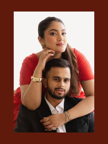 A bold and stylish indoor portrait. The bride's striking red dress and the couple's confident pose create a modern and effortlessly elegant image, showcasing a different side of their personality.