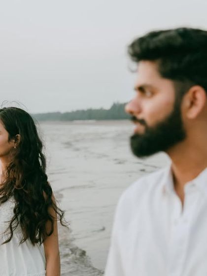 A quiet, contemplative moment on the beach. The focus on her with him slightly blurred in the foreground creates a sense of depth and story.