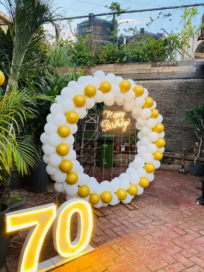 A 70th birthday celebration with a simple yet elegant white and yellow balloon ring and marquee numbers.