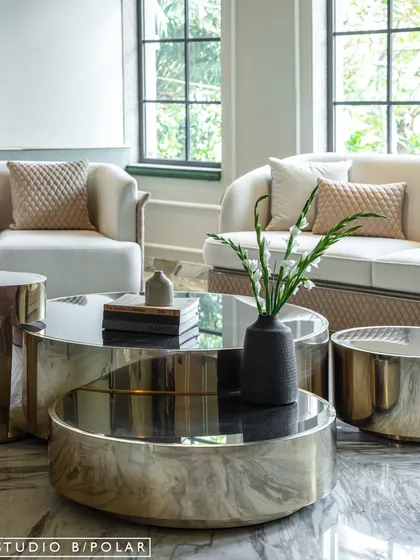 A close-up of the nested coffee tables, which feature a mix of polished metal and black glass. The combination of materials and curved forms adds a sculptural quality to the space.