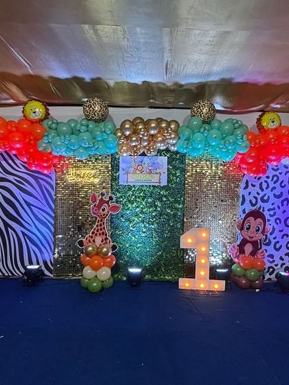 A vibrant and fun jungle theme for Hitanshu's 1st birthday. This setup used shimmering sequin panels in gold and green, animal print backdrops, and cute character cutouts to create a wild and festive photo corner.