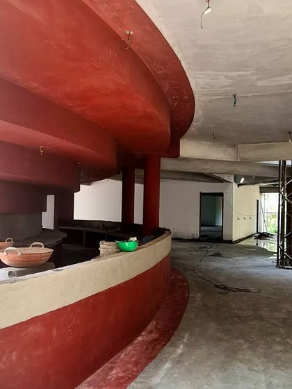 A view of the curved bar at the TAPMI Centre during construction, its form accentuated by the continuous red oxide finish.