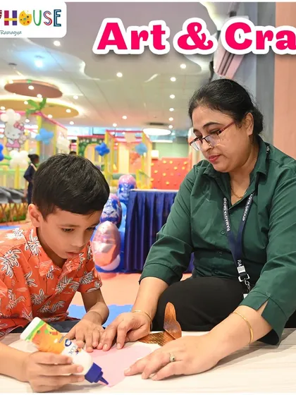 An art and craft session in full swing. A staff member guides a young boy as he works on his creation, fostering learning and fun.
