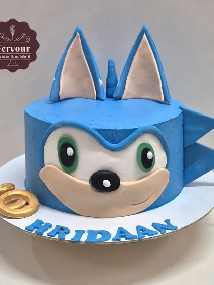 A super Sonic the Hedgehog theme cake. This design is shaped like Sonic's face and is made with zero fondant, using skillfully piped whipped cream to create the iconic character.