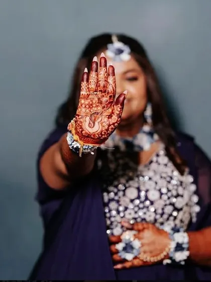 A stylish shot of a bride showing her palm, with a beautiful Ganesha design, to the camera.