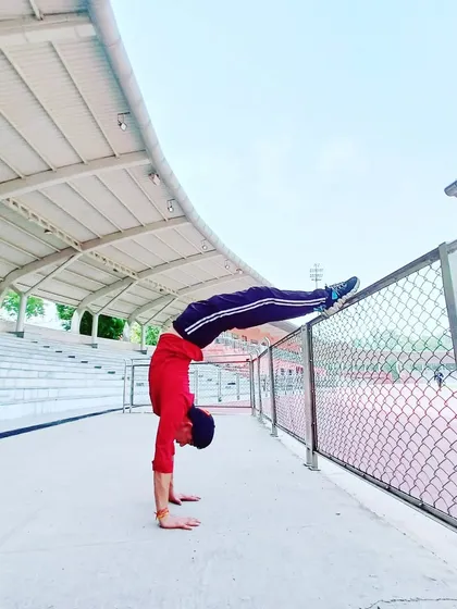 A handstand variation at an outdoor stadium, showing that yoga can be practiced anywhere, turning the world into your studio.