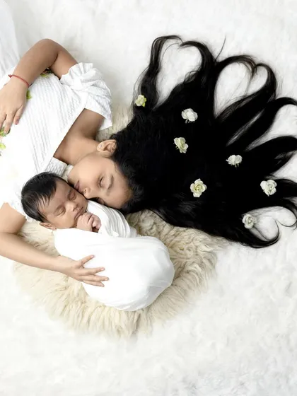 A beautiful overhead shot of an older sister protecting her newborn sibling, with her hair arranged in heart shapes.